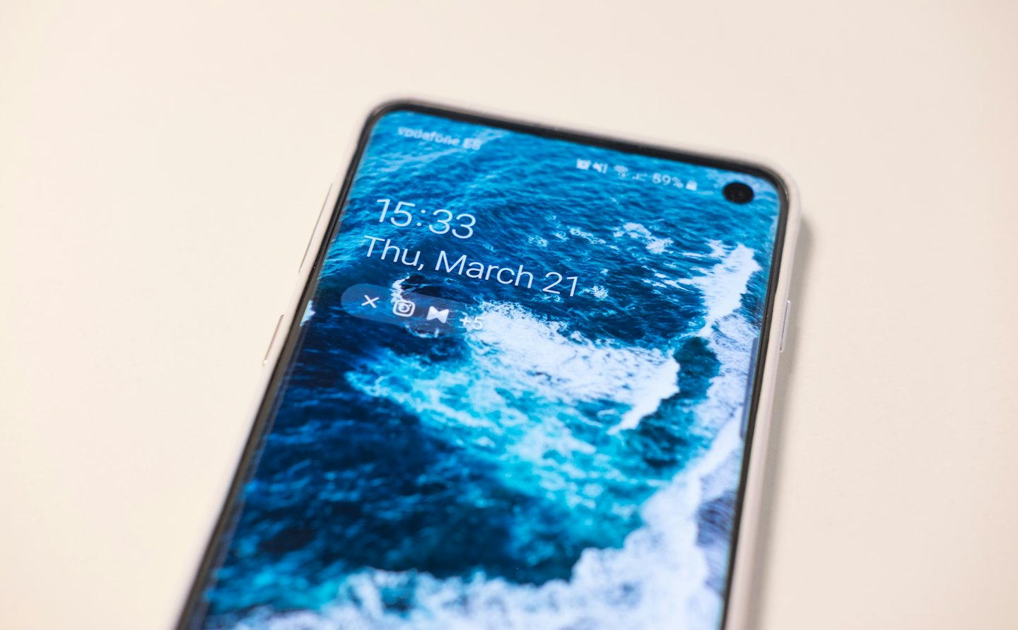 Uno smartphone moderno mostra una schermata di blocco con un'onda dinamica dell'oceano.